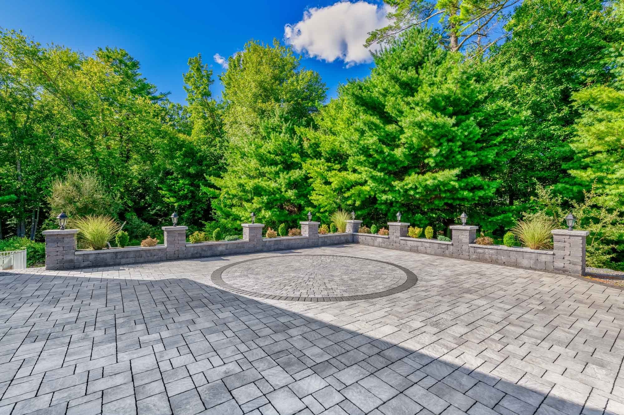 Wide view of the driveway circle, contrasting border, and low masonry wall.