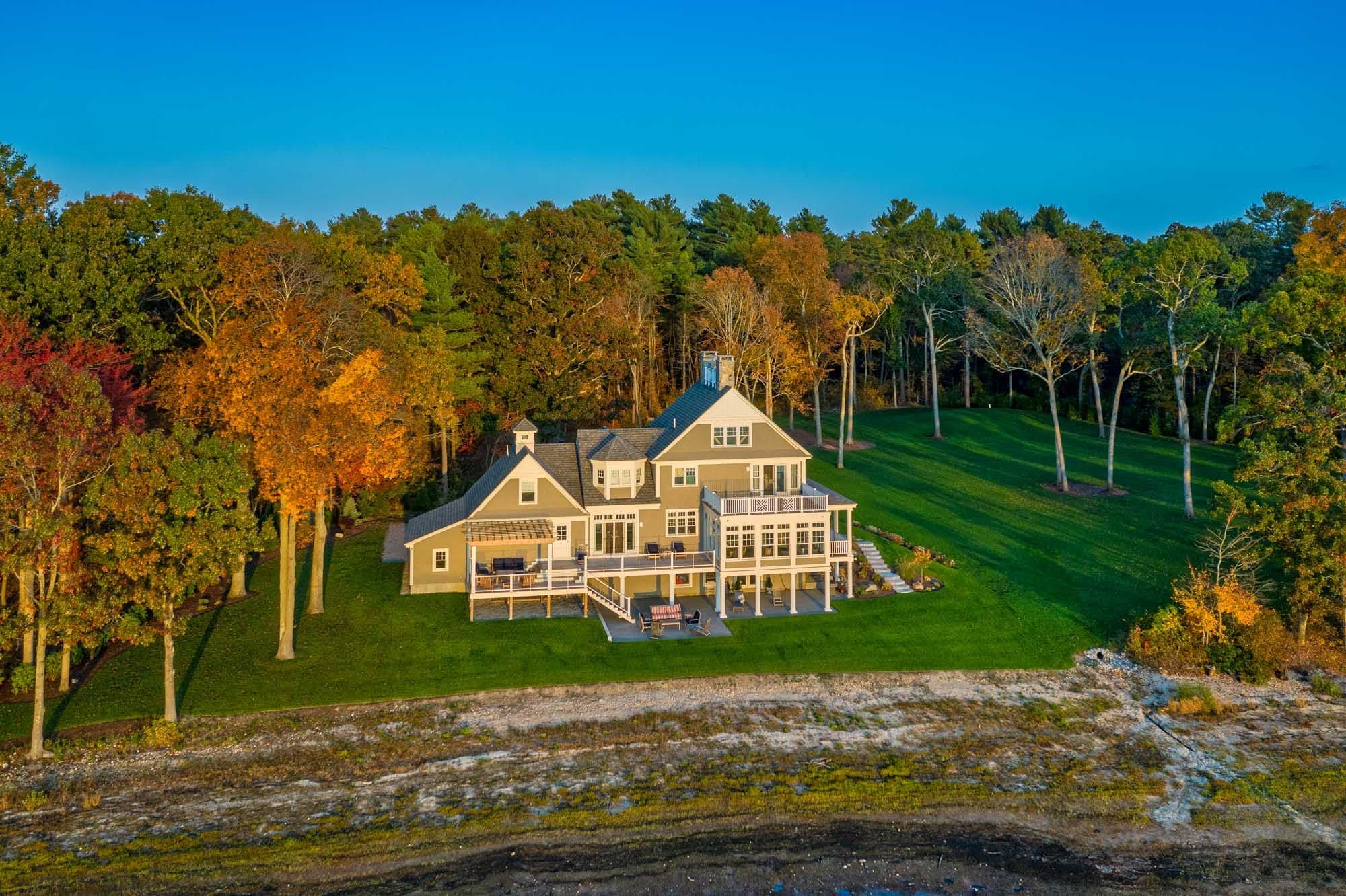 Wide aerial view of the shoreline, house, and wooded lawn in Pembroke.
