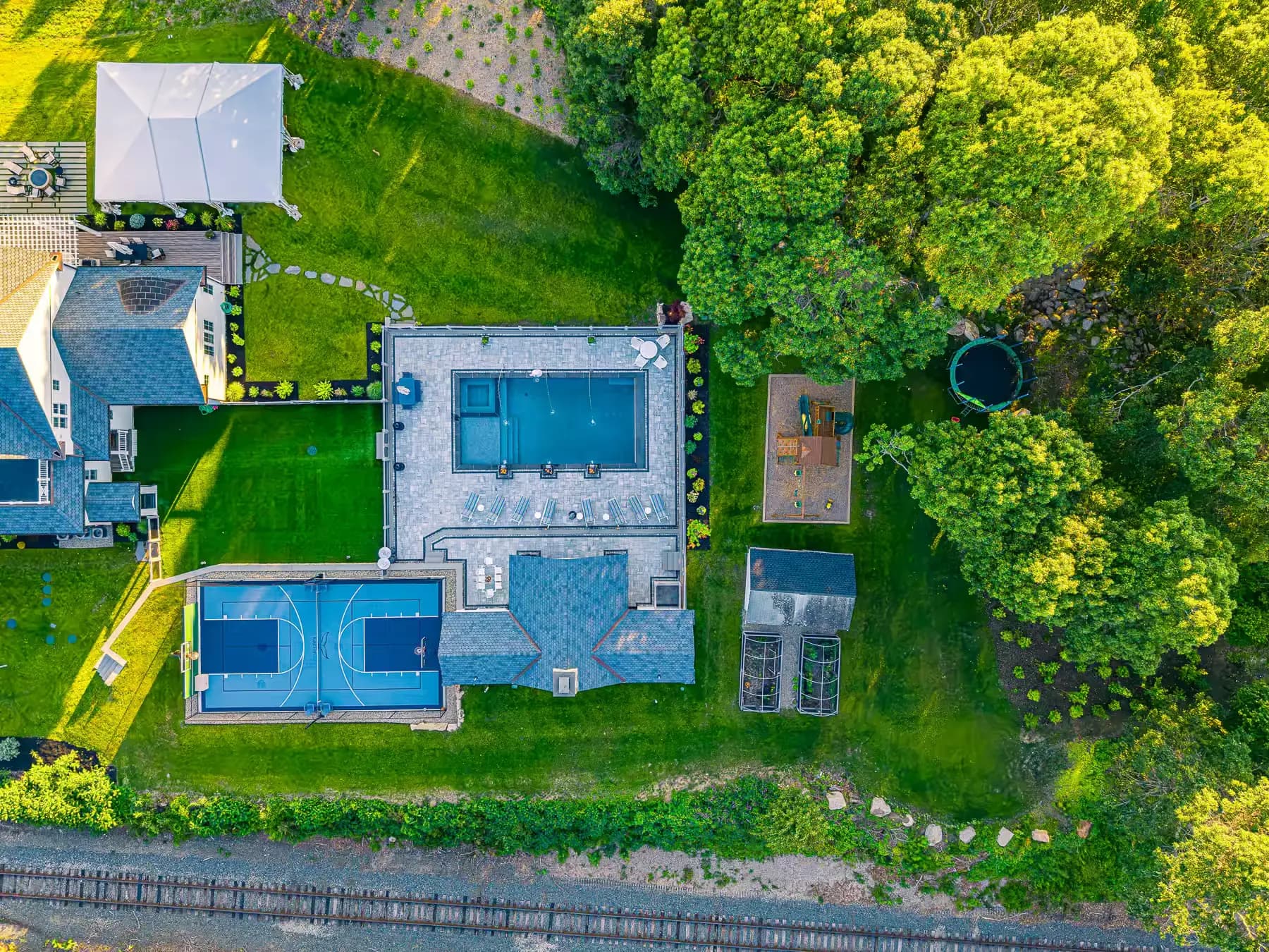 Overhead view of the rectangular pool, inset spa, lounge seating, and adjacent basketball court.