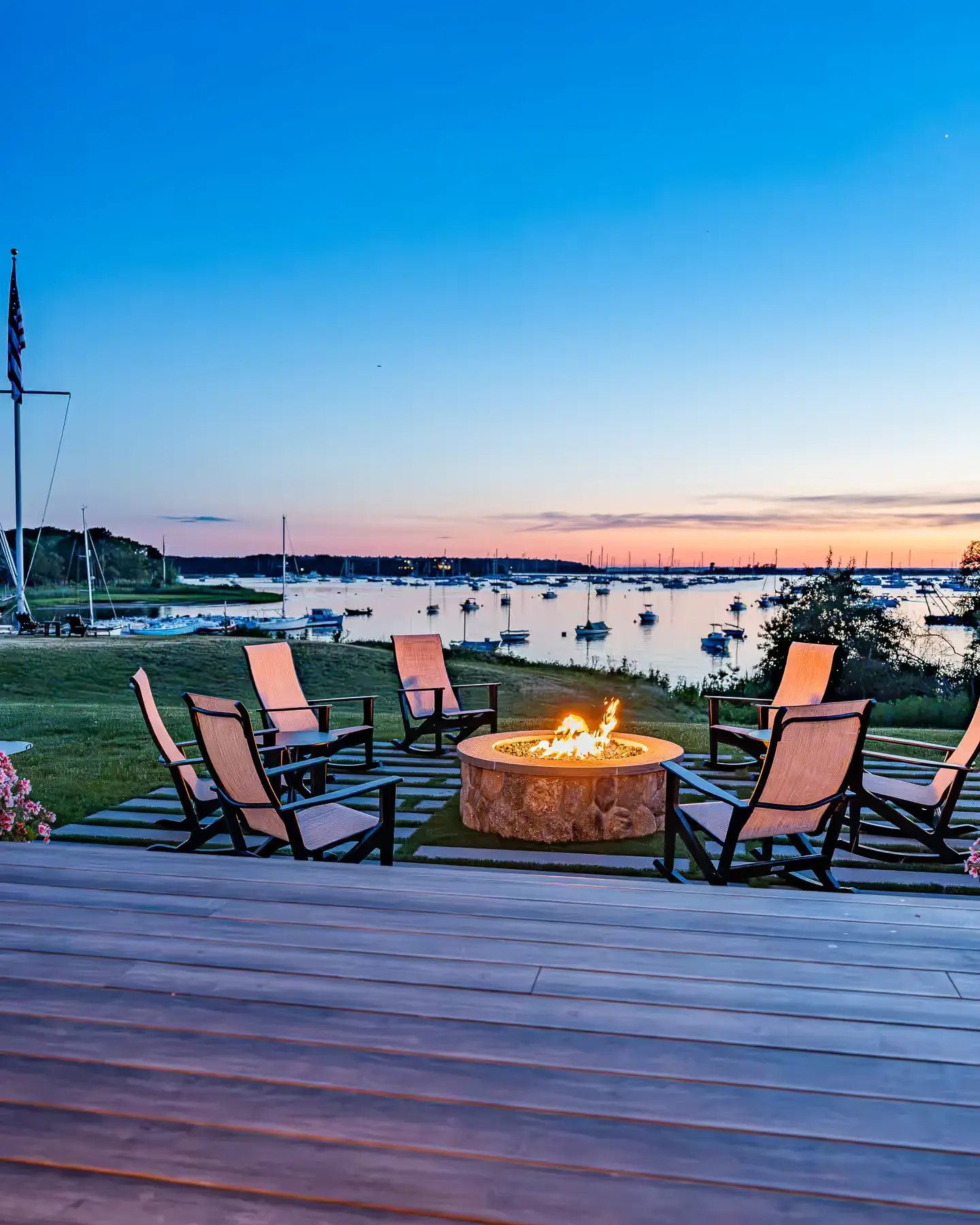 Waterfront fire-pit seating beside the deck, overlooking the harbor at sunset.