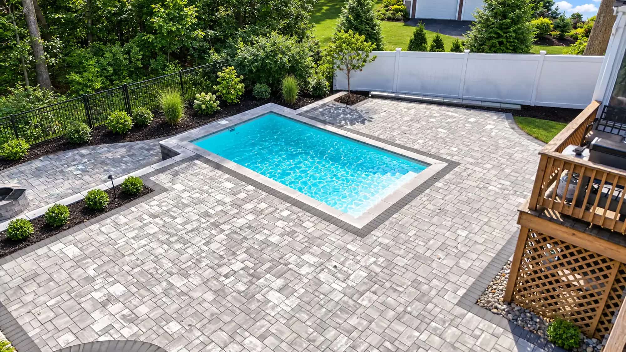 Raised plunge pool set in a paver patio with planting beds and a wood deck in Mansfield, MA