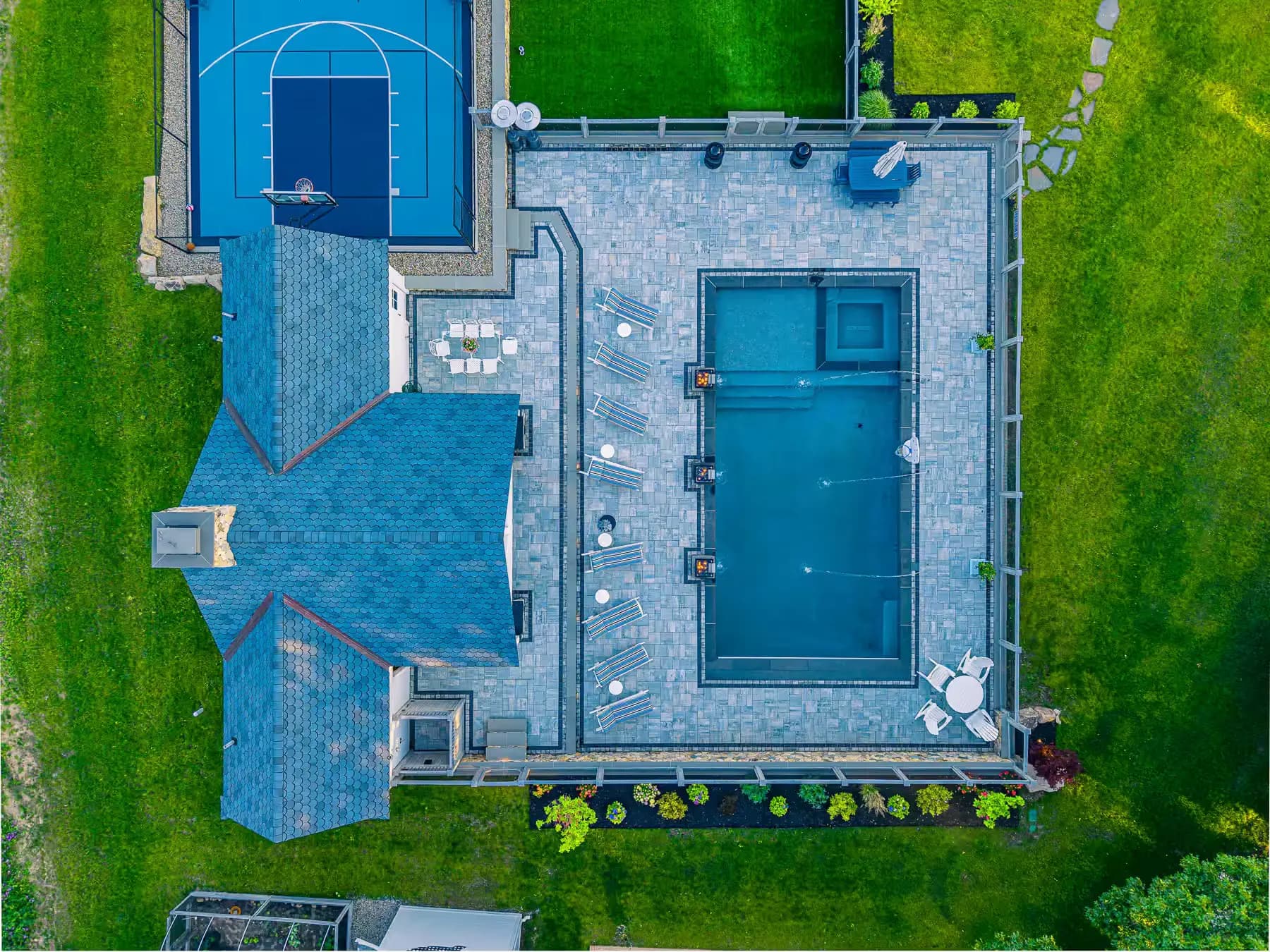 Pool and inset spa surrounded by patterned paving, with the pavilion and sport court alongside.