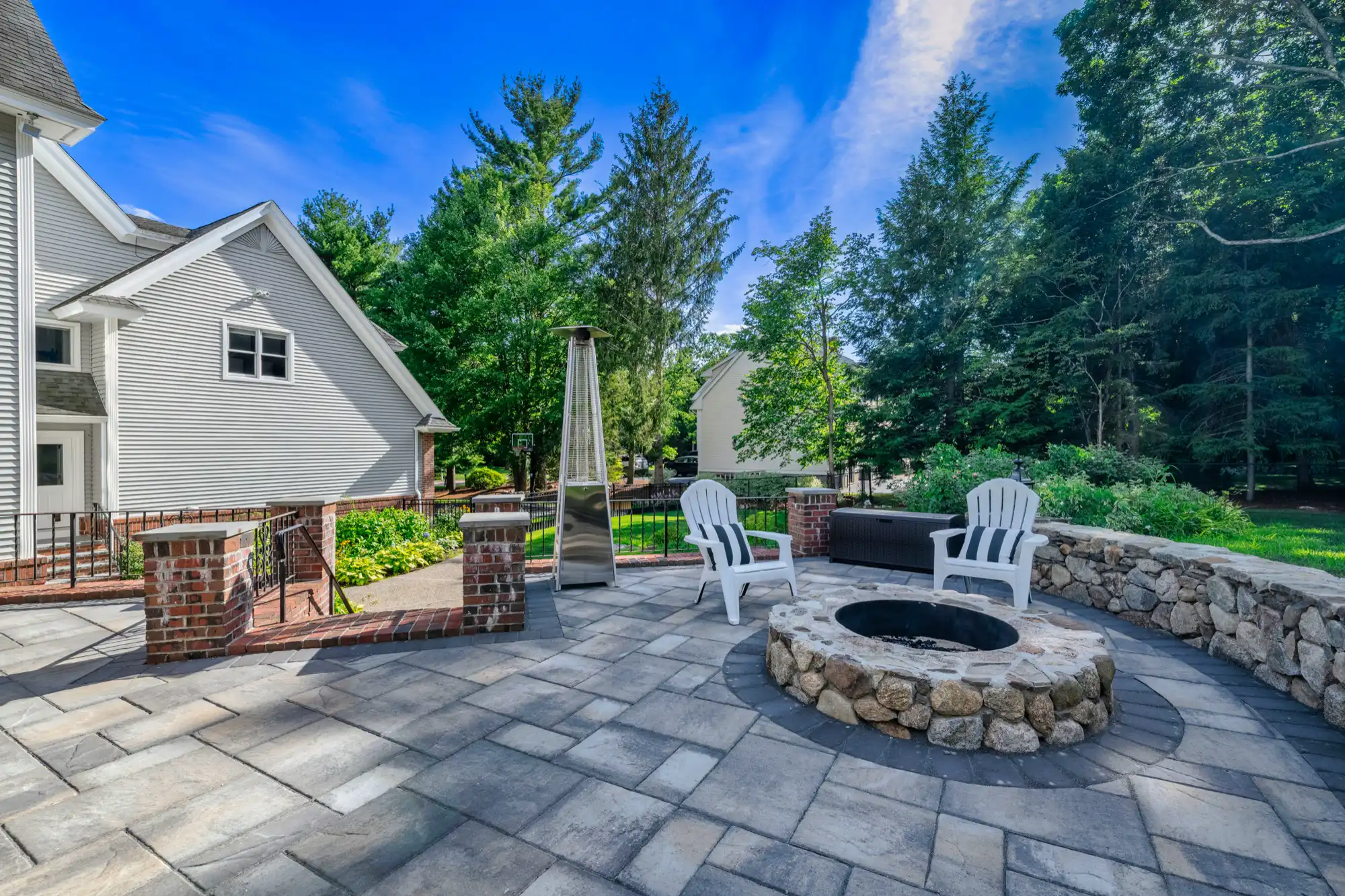 Round stone fire pit and Adirondack chairs within the curved patio edge.