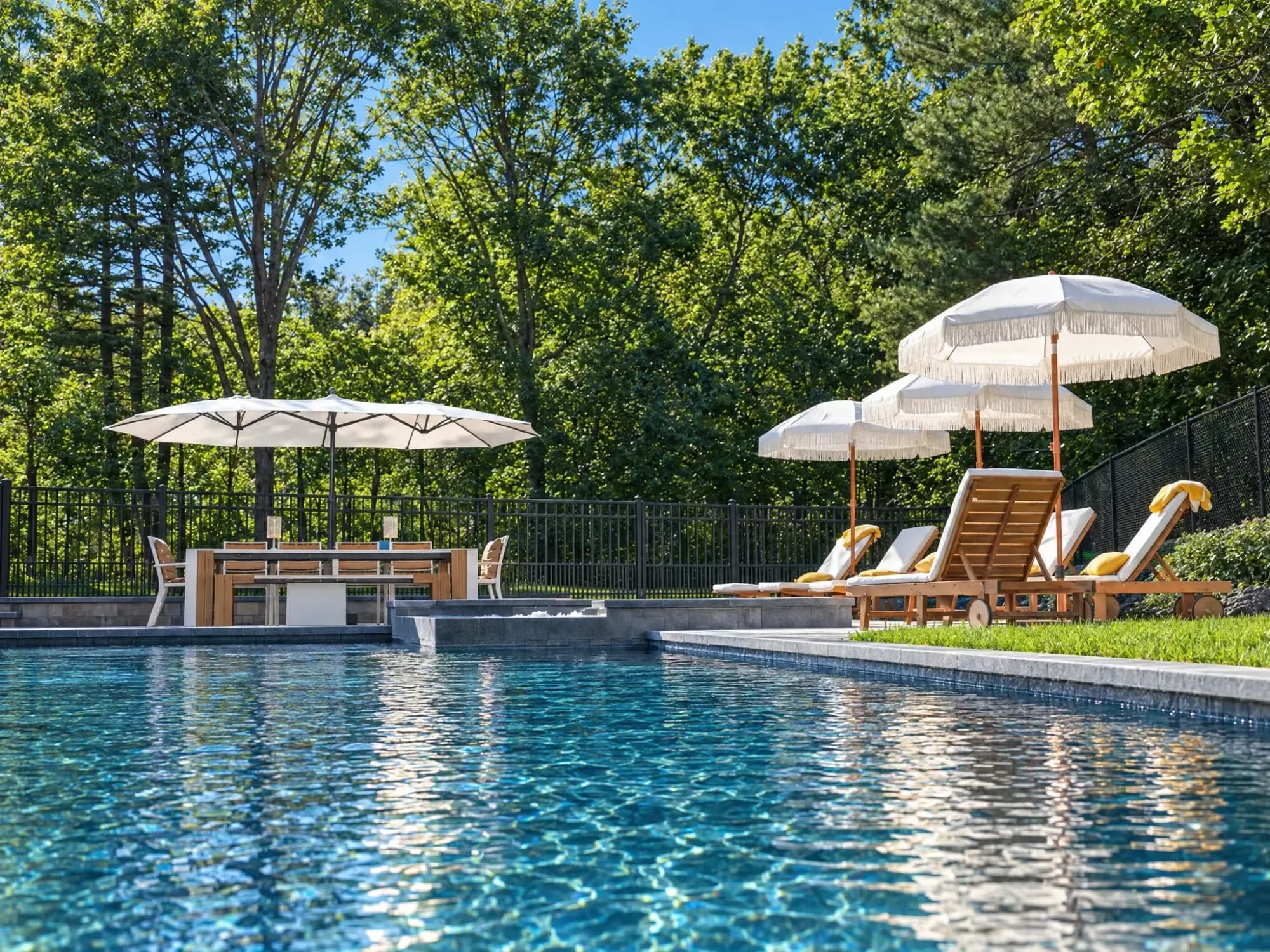 Water-level view across the Easton pool toward the raised spa and shaded poolside seating.