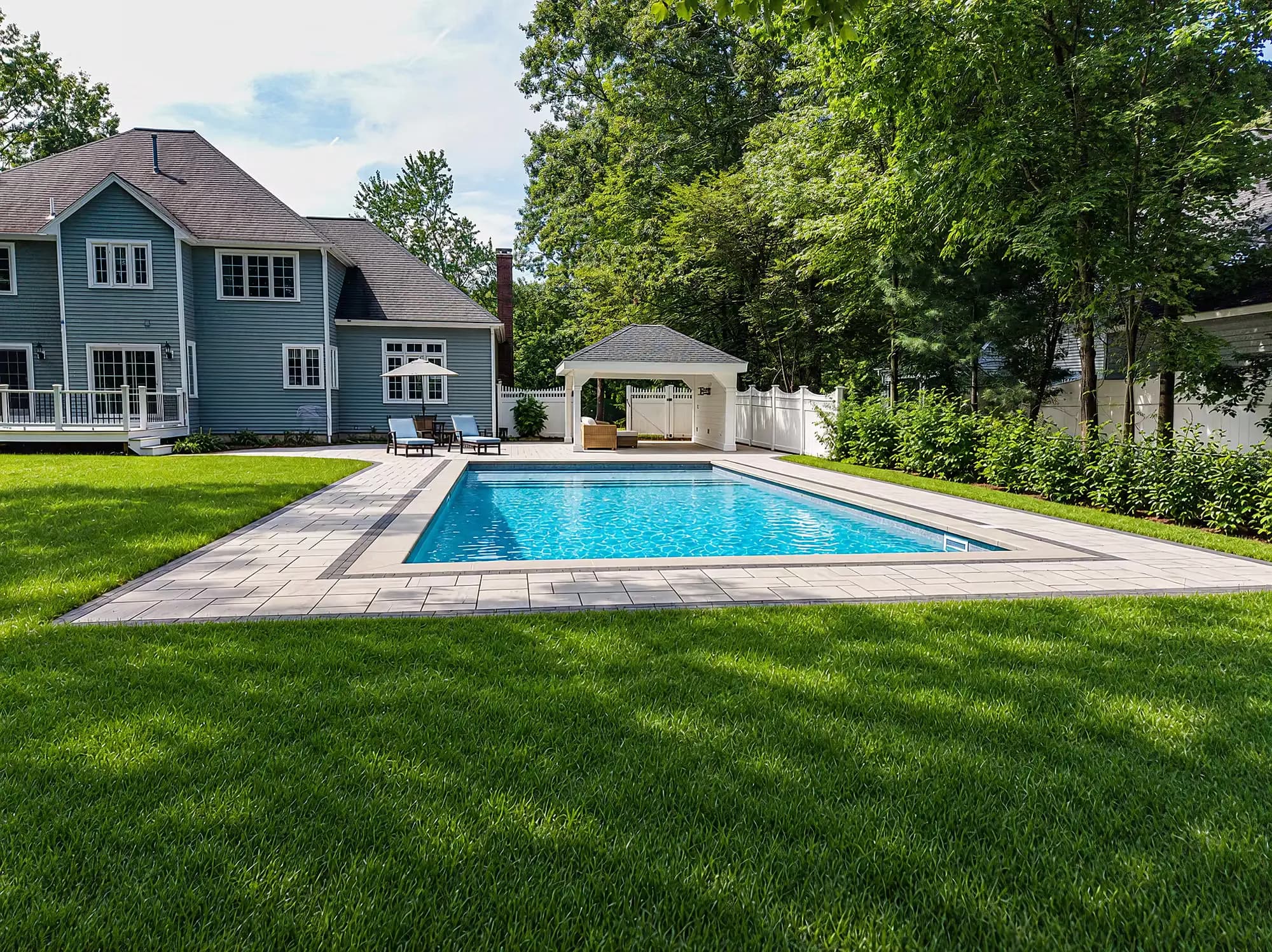 Lawn-level view of the pool deck and pavilion behind the Mansfield home.