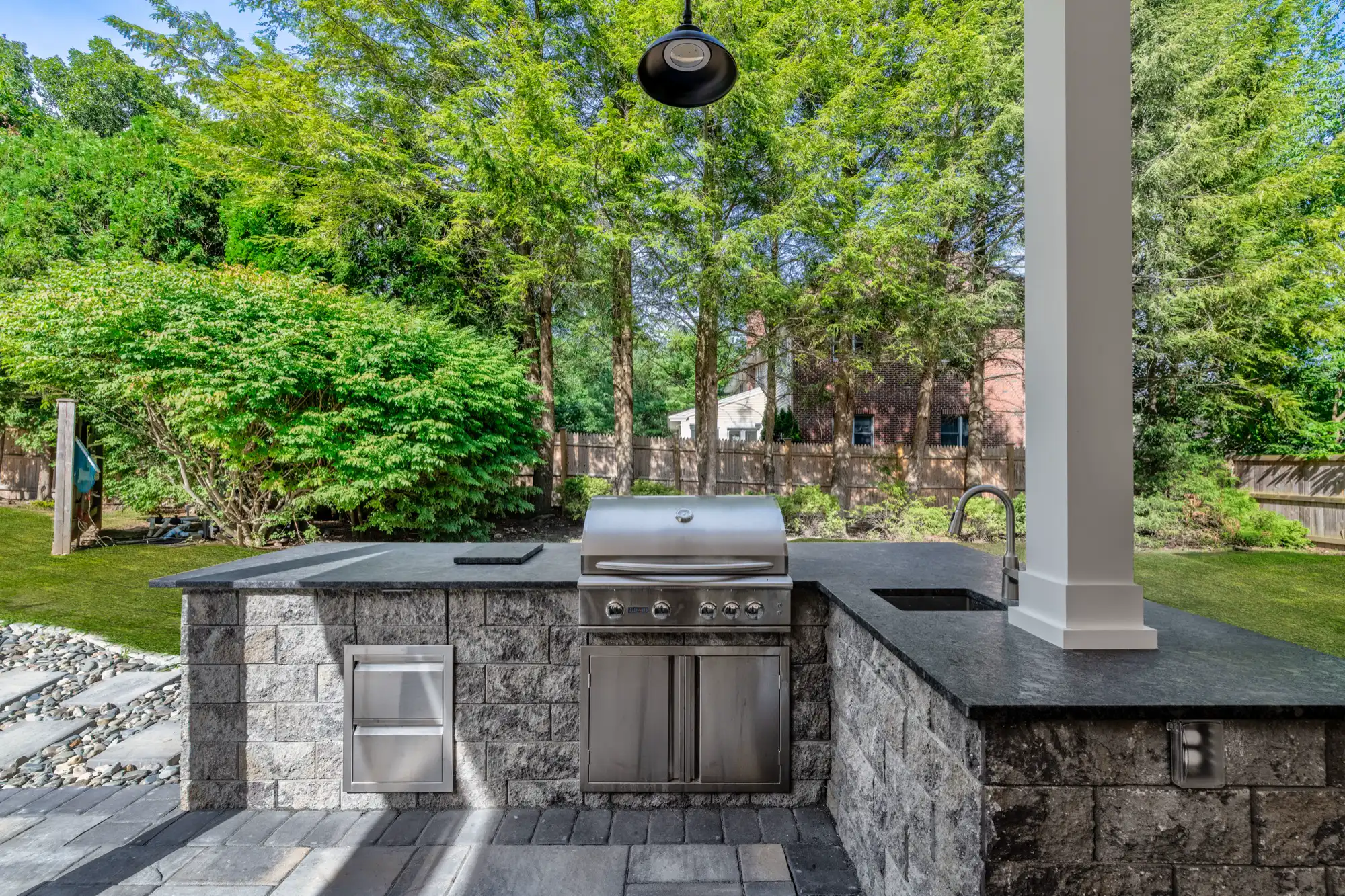 Built-in grill and dark counters in the stone-faced outdoor kitchen.