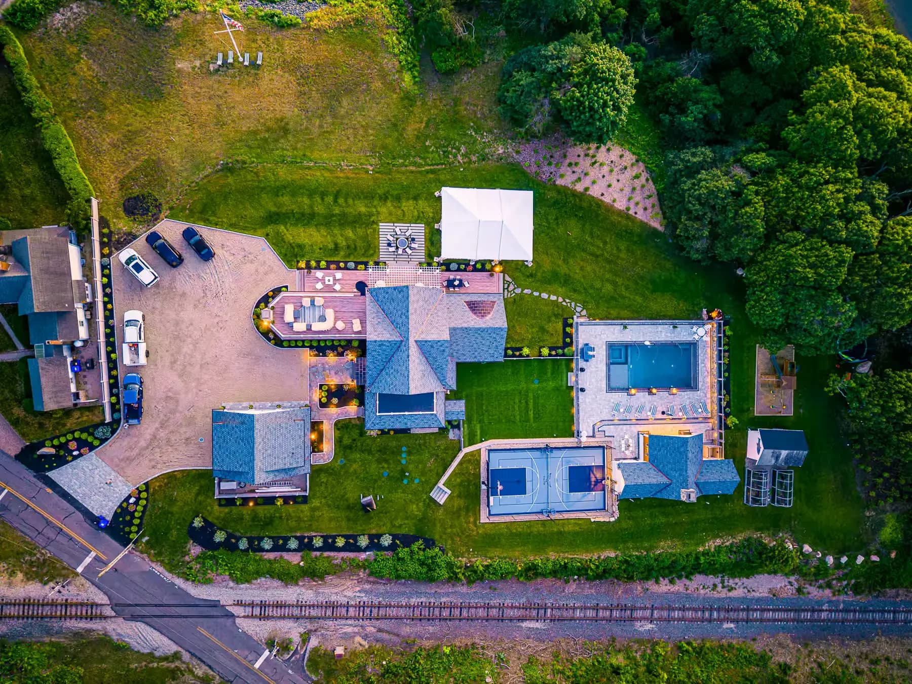 Overhead view showing how the paved arrival area, buildings, lawn, pool, and sport court fit together.