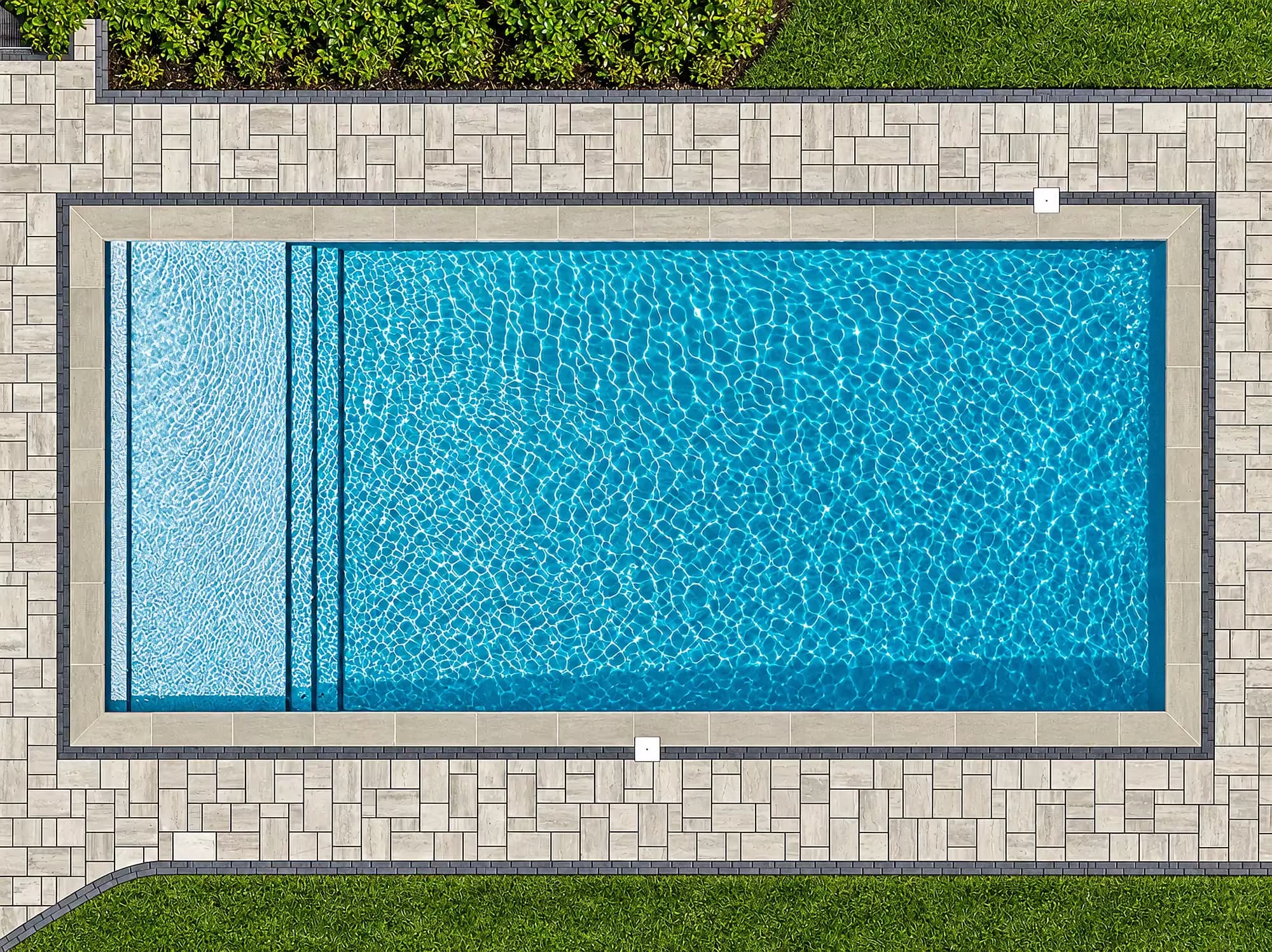 Overhead view of the pool, light coping, dark border course, and multi-size pavers in Mansfield, MA.