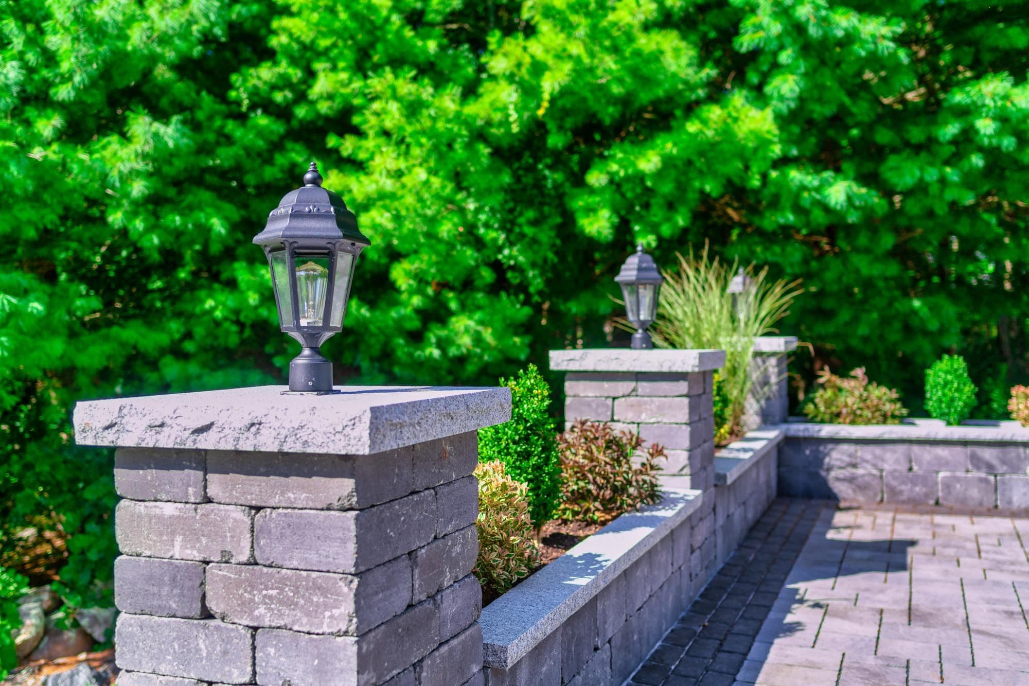 Capped masonry pillars with black lanterns along the driveway wall in North Easton.