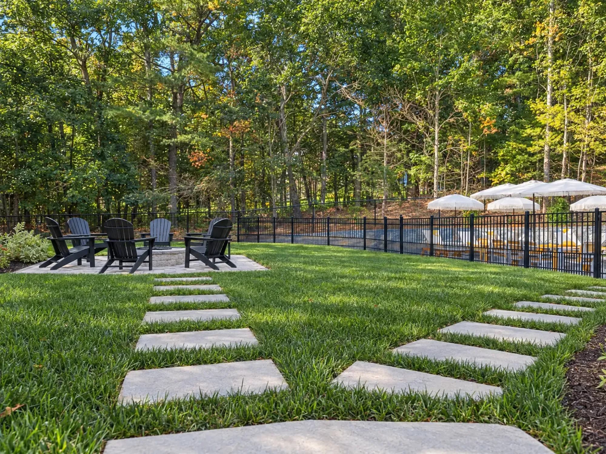 Stepping-stone paths connect the fire-pit patio and fenced pool terrace across the Easton lawn.