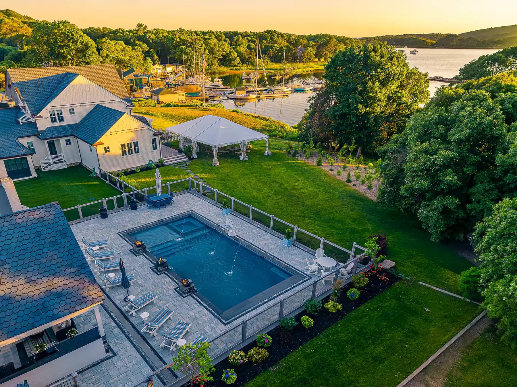 Elevated view across the pool terrace toward the waterfront and surrounding lawn.