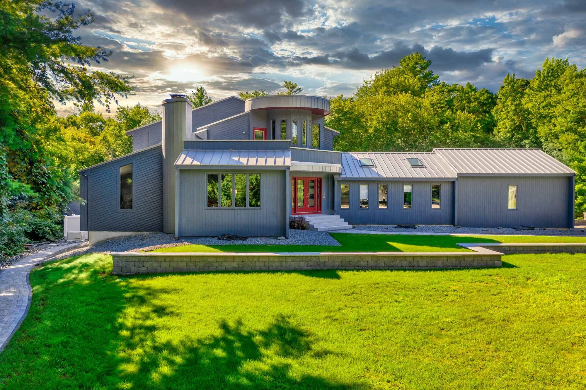 Wide view of the home, front garden wall, lawn, and connecting entry paths.