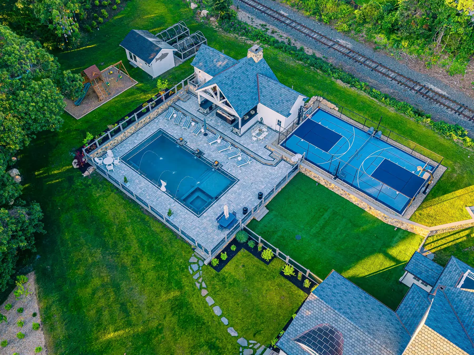 Aerial view of the Buzzards Bay pool terrace, covered pavilion, sport court, and connecting lawn paths.