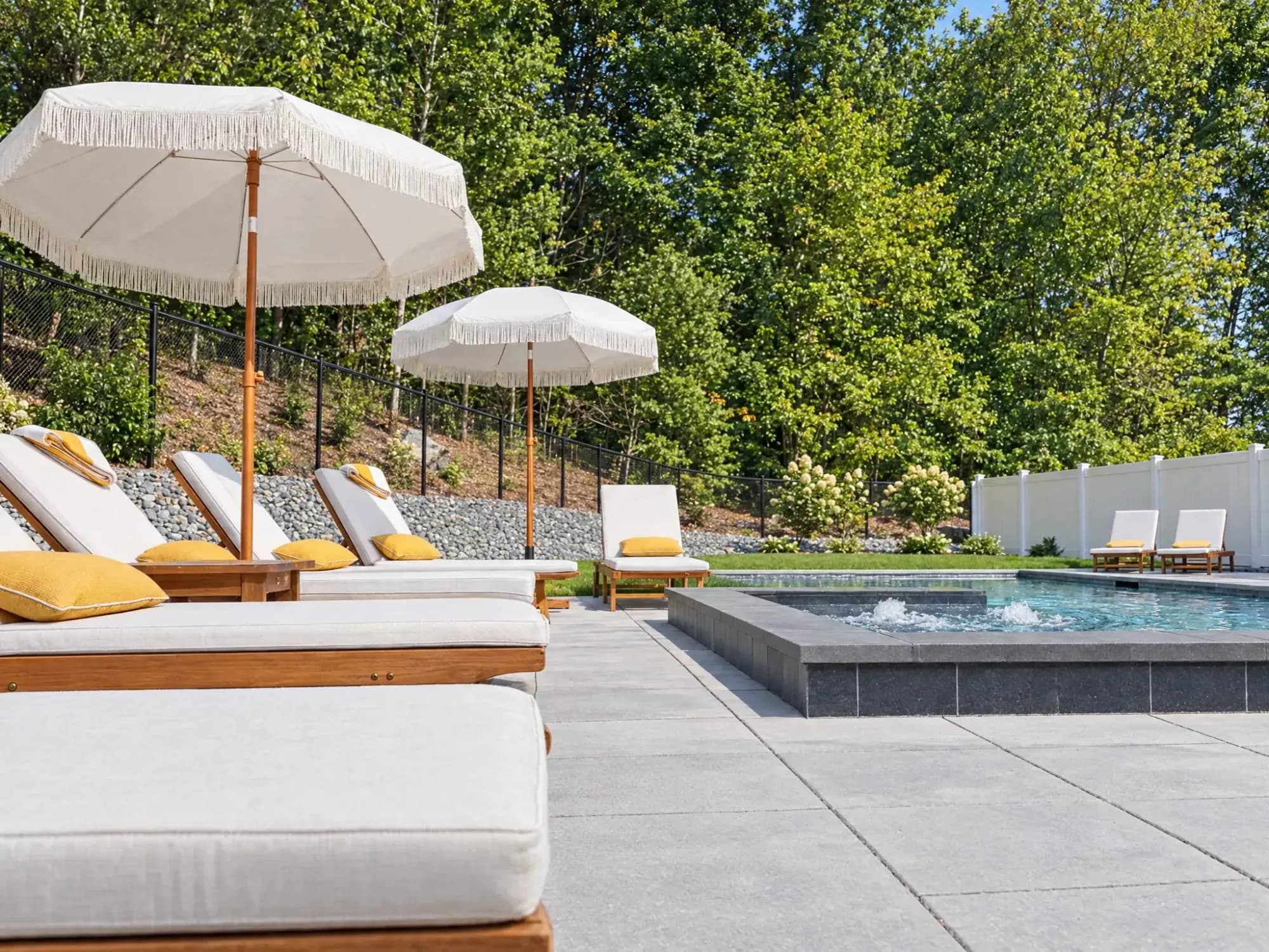 Close view of the raised spa, gray paver terrace, and poolside lounge chairs in Easton, MA.