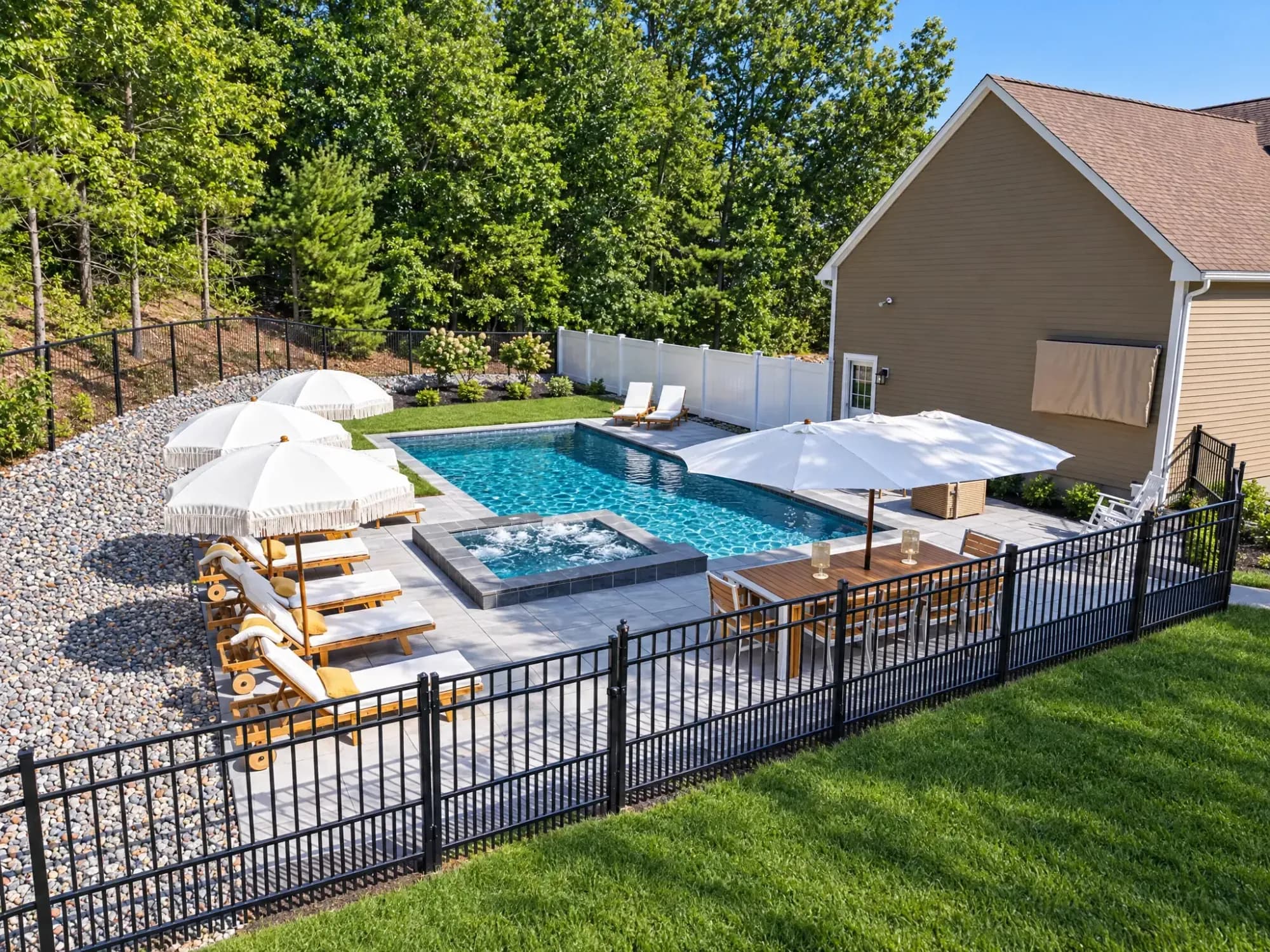 Elevated view of the Easton pool and spa beside the house, with a paver patio and dining area.