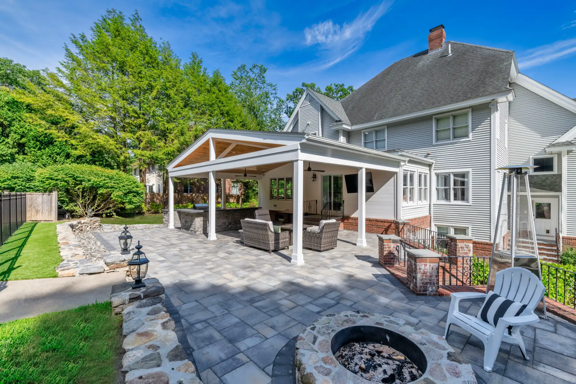 Wide view of the house, pavilion, paver terrace, and round fire pit.