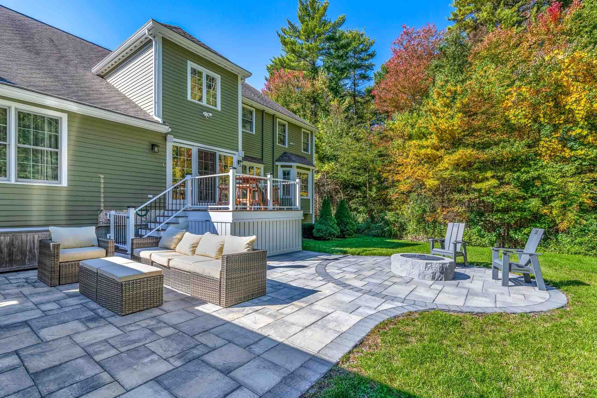 Open paver patio connecting the house steps, lounge seating, and circular fire-pit area.
