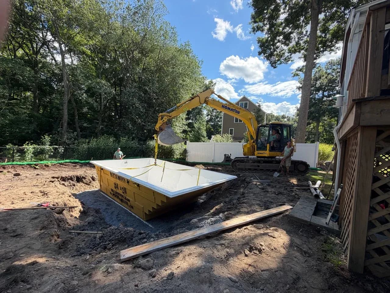 White Okeanos fiberglass pool shell being set into a backyard excavation.