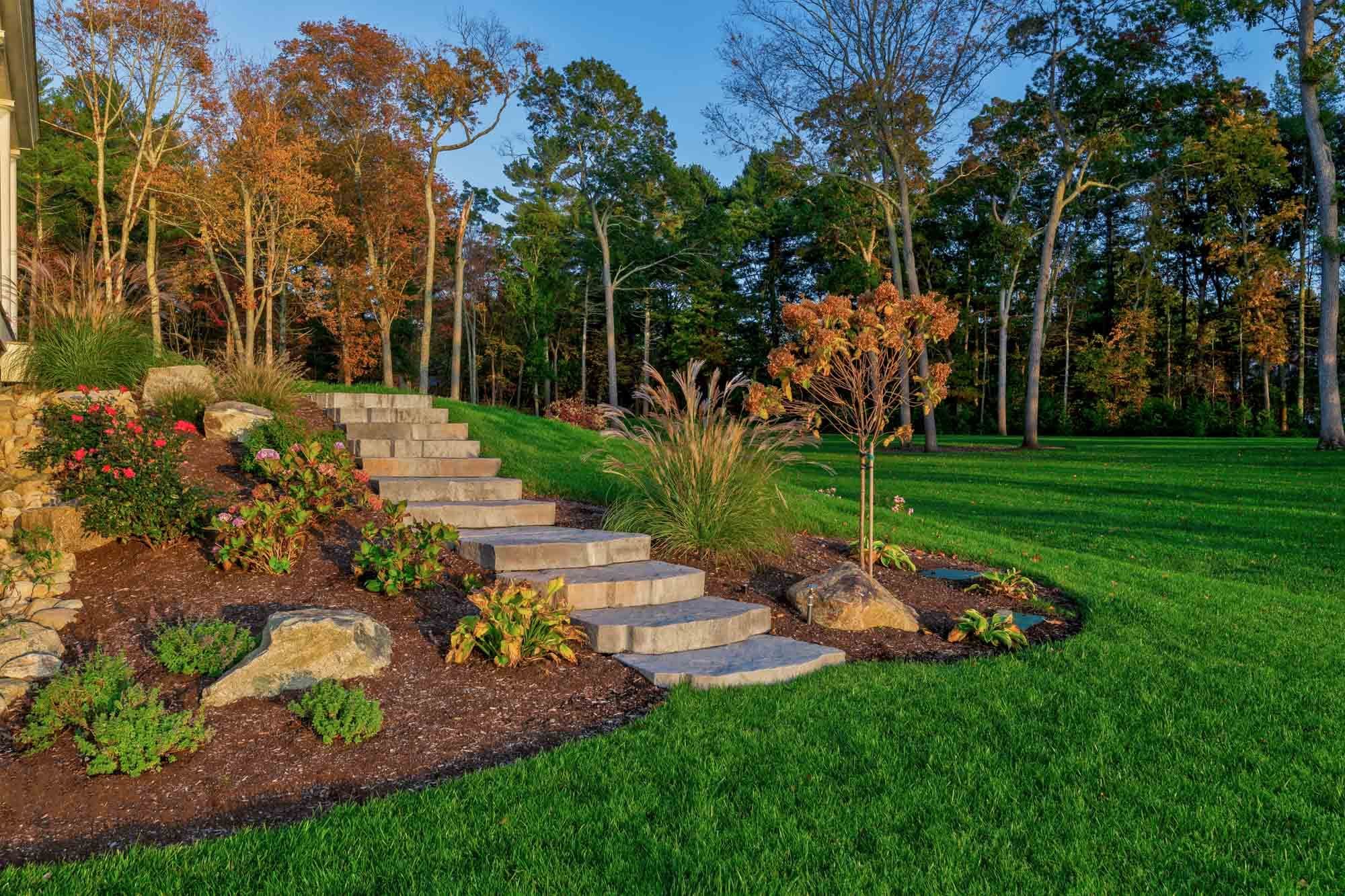 Broad stone steps climb through planted beds and landscape boulders beside the Pembroke lawn.