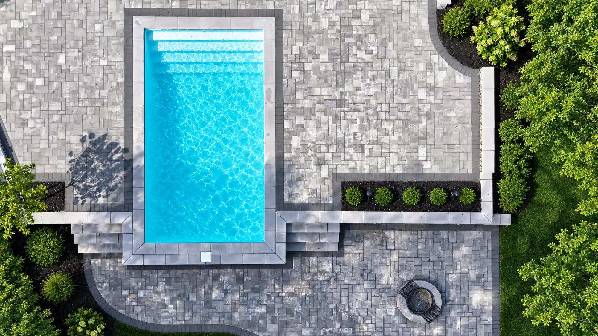 Overhead view of the pool, coping, paver patios, wall steps, and fire pit in Mansfield, MA.