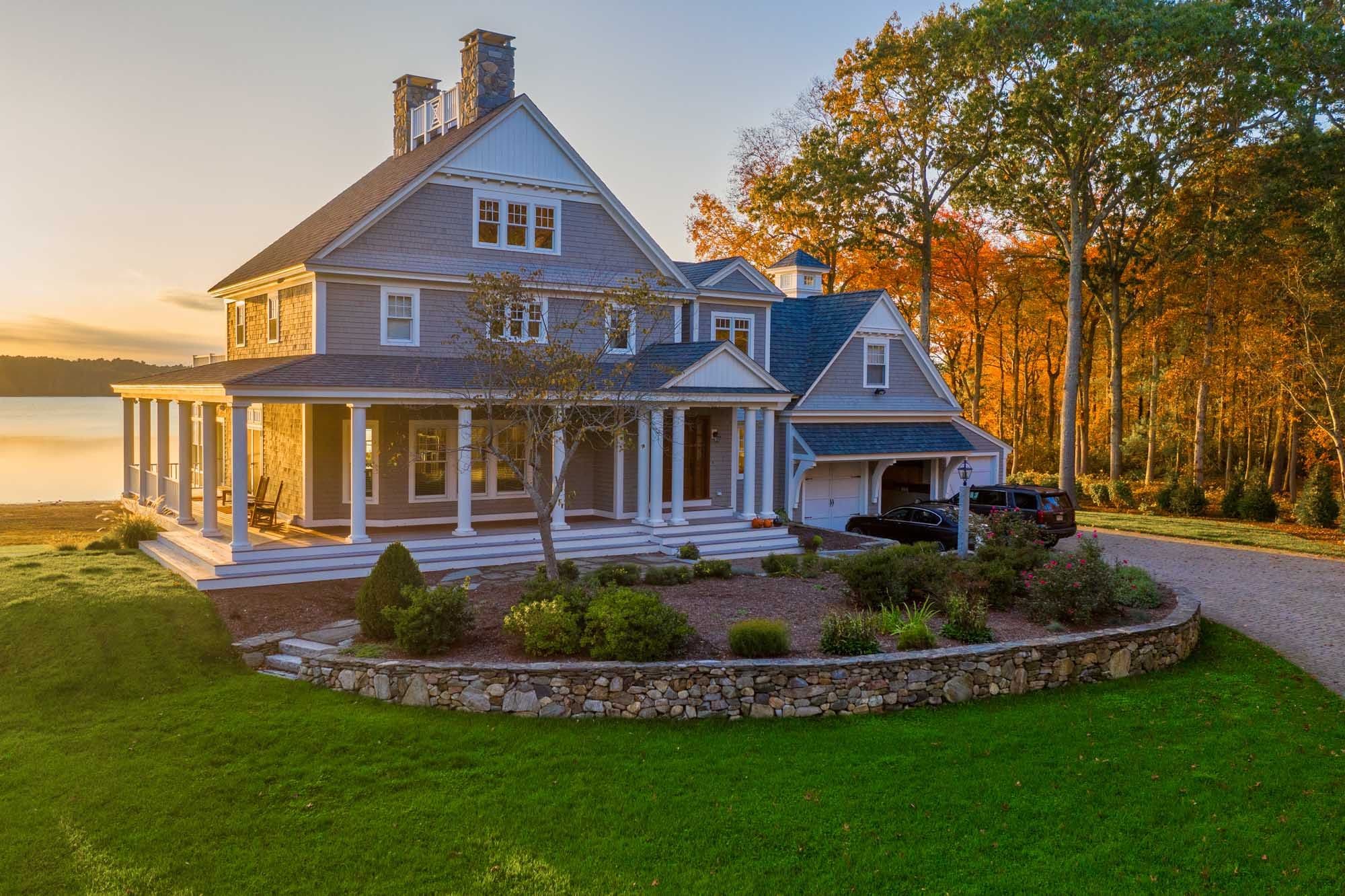 Curved stone planting wall and garden beds beside the house at sunset.