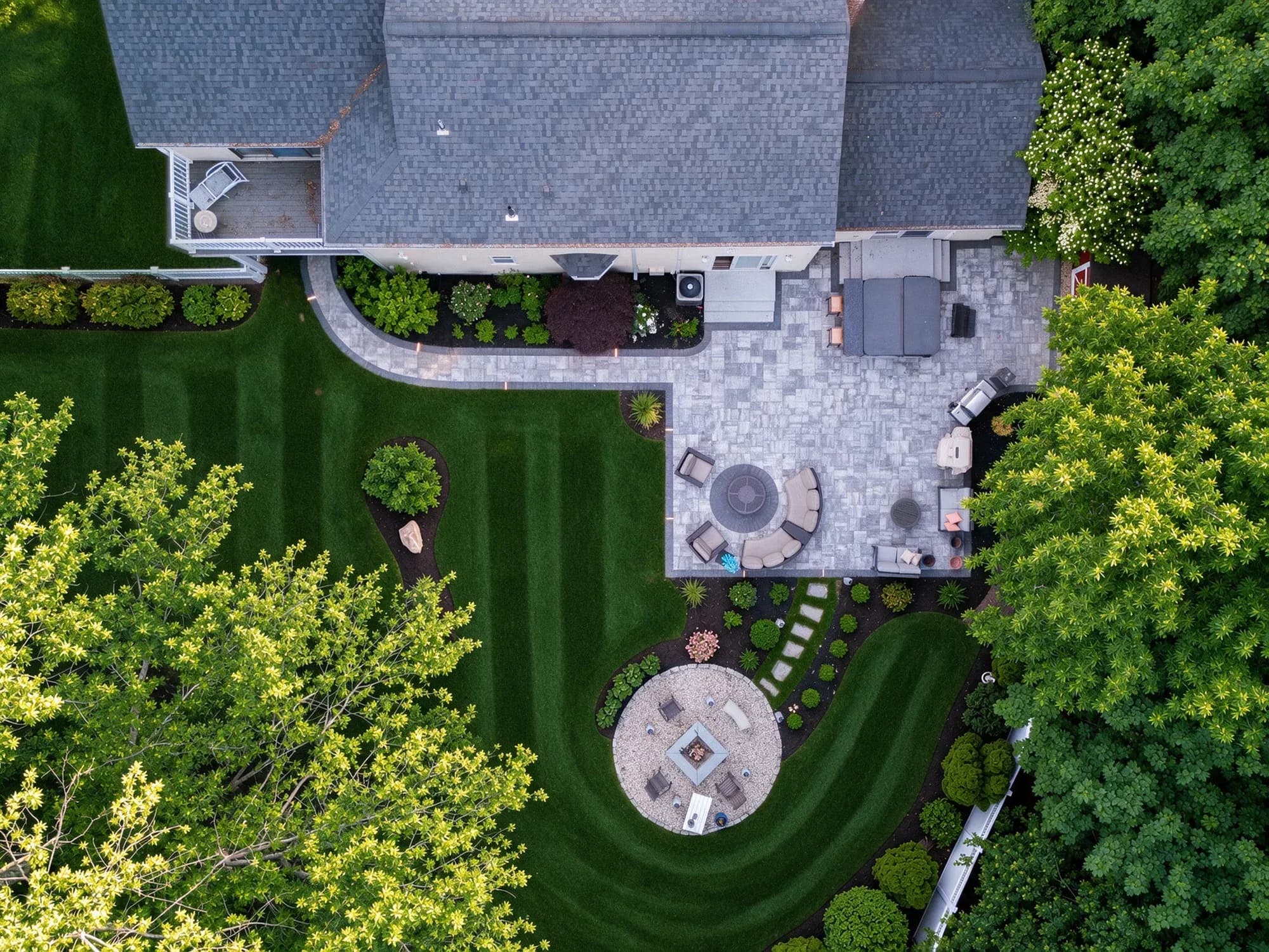 Overhead view of the paver patio, curved walkway, lawn, and circular fire-pit area in Westwood, MA.