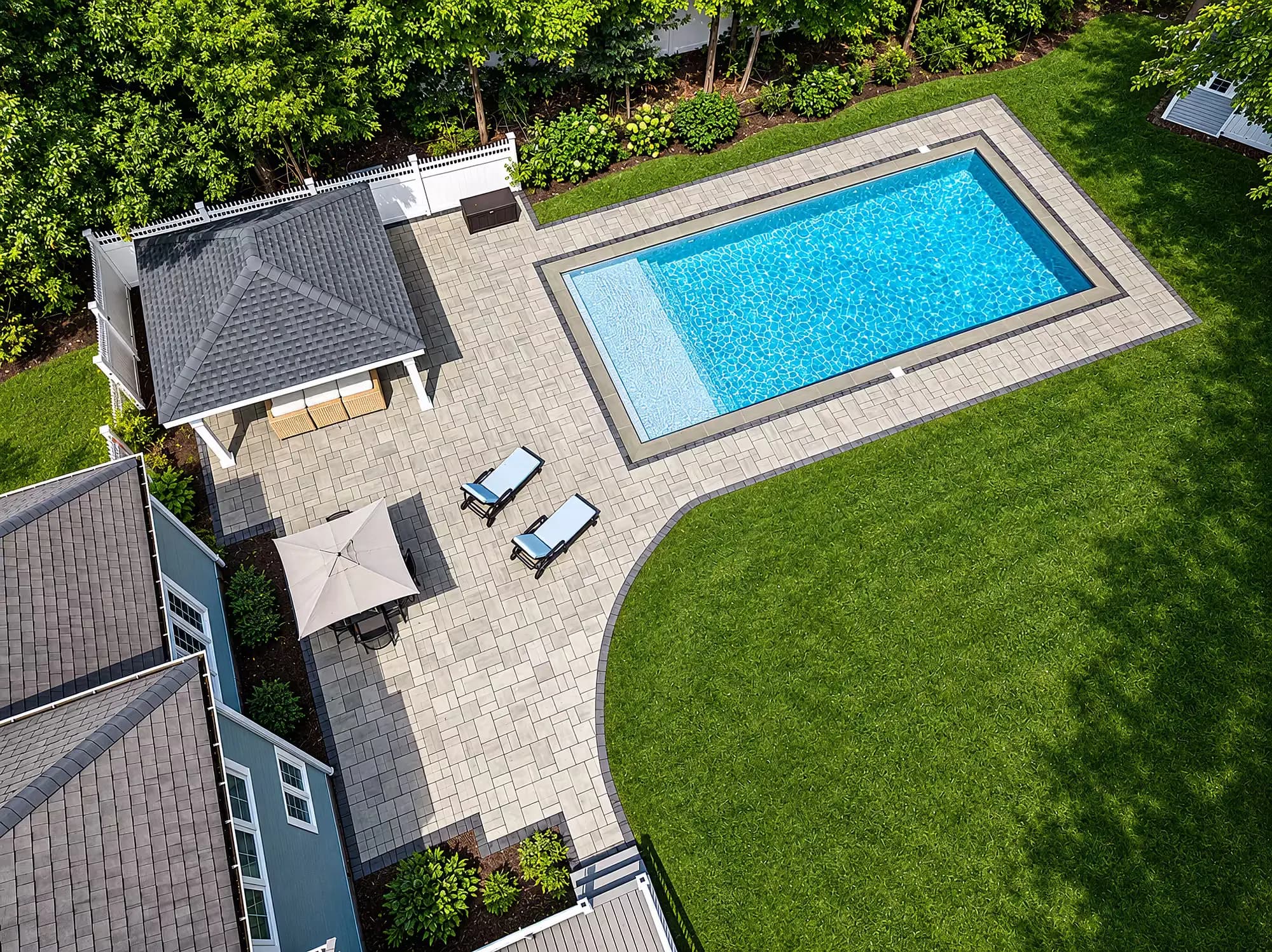 Aerial view of the patio, pavilion, and pool deck with a curved border along the lawn in Mansfield, MA.